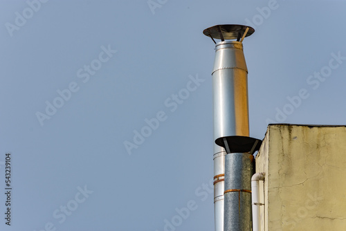 Industrial chimneys with cowl made of metal material installed on the exterior wall of a factory wall
