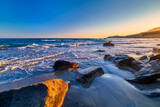 Beautiful seascape of low tidal waves, clear sunset sky, hazy hills