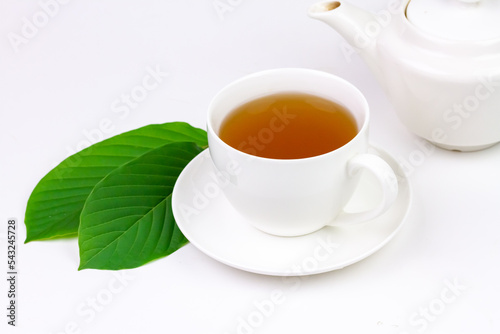 Mitragyna Speciosa Korth or kratom tea in white cup wtih green leaf isolated on white background.