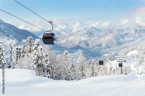 New modern spacious big cabin ski lift gondola against snowcapped forest tree and mountain peaks covered in snow landscape in luxury winter alpine resort. Winter leisure sports, recreation and travel