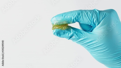 Worker use two finger and squeeze lithium grease and see the fiber of grease in the laboratory isolated on white background. Yellow transparence grease on the finger. Testing and manufacturing concept
