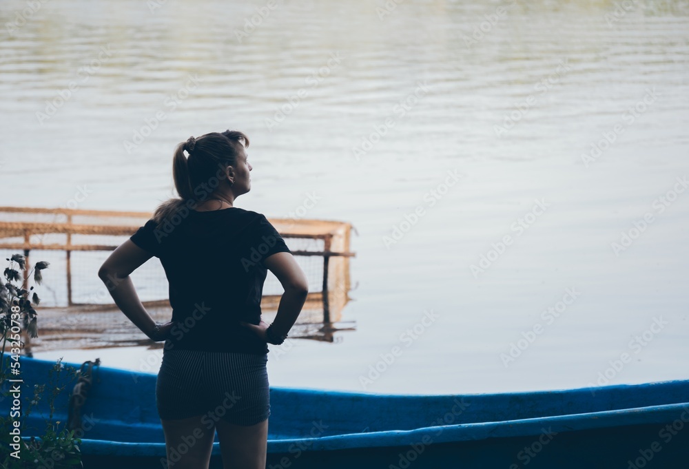 Woman stands in front of boat and fishing net looking away