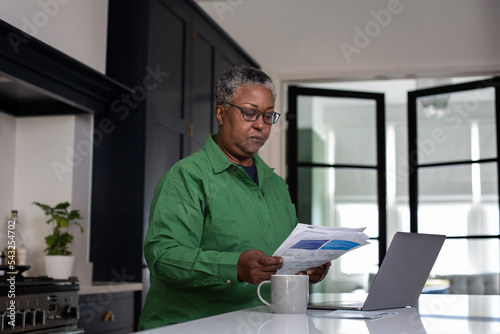 Senior african american female at home looking at bills and personal finances using a laptop