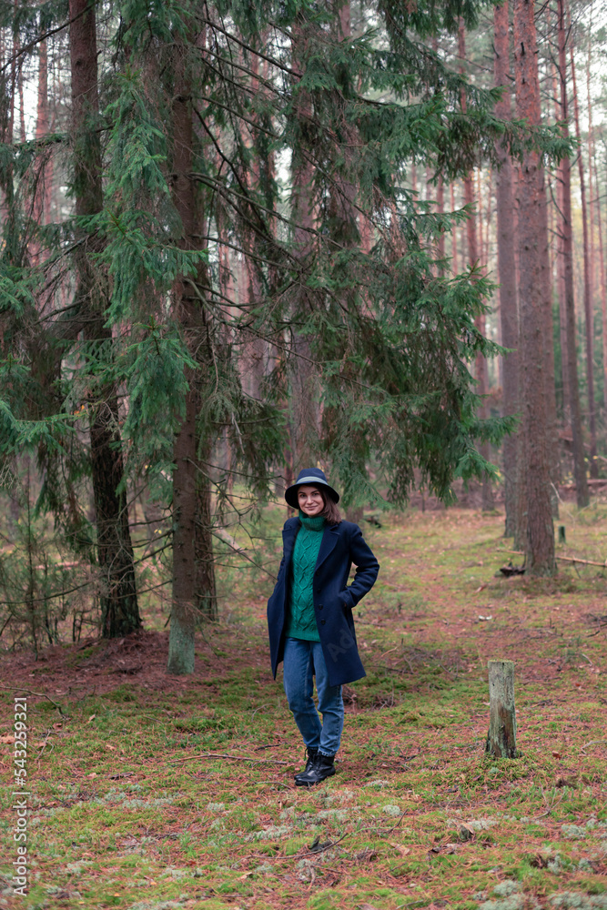 Happy young woman in a hat walking in forest and exploring local nature Happy young woman in a hat walking in forest and exploring local nature