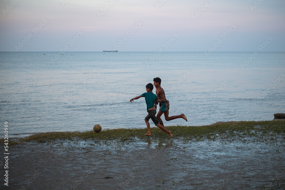 South asian rural teenage boys playing football at a wet ground near a river just before the fifa world cup South asian rural teenage boys playing football at a wet ground near a river just before the fifa world cup