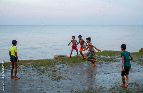 South asian rural teenage boys playing football at a wet ground near a river just before the fifa world cup 