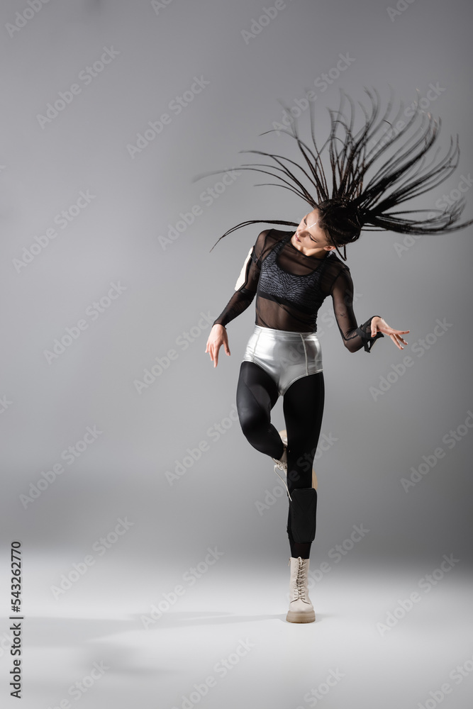 full length of expressive futuristic style woman with braids posing on grey background. full length of expressive futuristic style woman with braids posing on grey background.