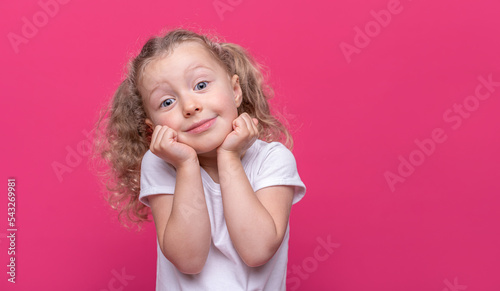 Happy little girl is showing glasses gesture on a pink background.