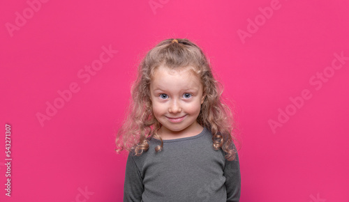 Little nice-looking lovely sweet curious cheerful girl on the pink color background.