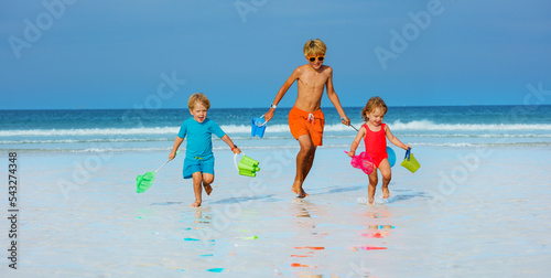 Three kids boys and a girl run from ocean with buckets