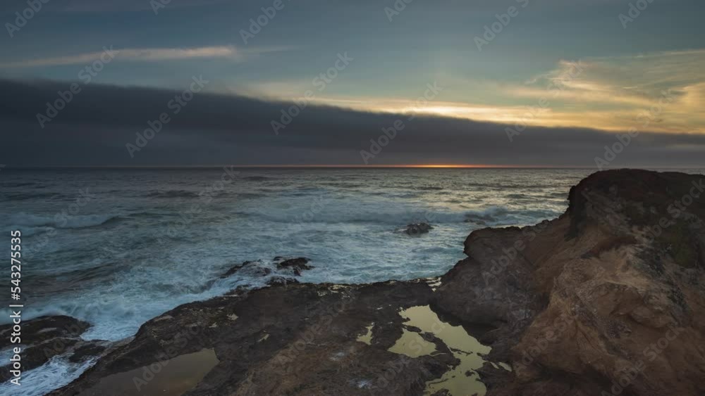 Sunset through gray clouds over coastal rocks - timelapse Sunset through gray clouds over coastal rocks - timelapse