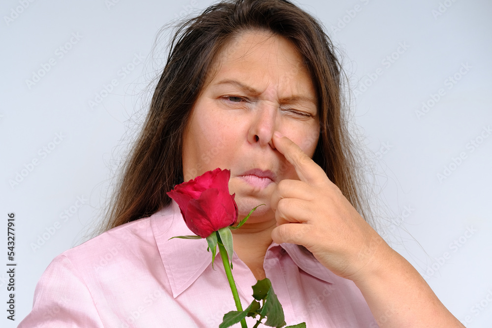 bouquet of flowers, red roses, unhappy middle-aged woman 50 years old with bulging eyes from bewilderment and surprise, dissatisfaction with gift, flower pollen allergy, emotional female portrait