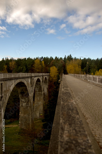 Stary betonowy most na wysokich filarach z lasem na horyzoncie na tle pięknego nieba.