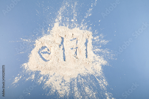 Titanium dioxide powder scattered on blue surface. TiO2 also known as titanium (IV) oxide or titania. Food additive, E171.  Inorganic compound, white chemical alimentary pigment photo