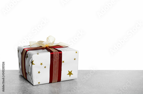 Christmas gift wrapped in star patterned paper on grey table against white background. Space for text