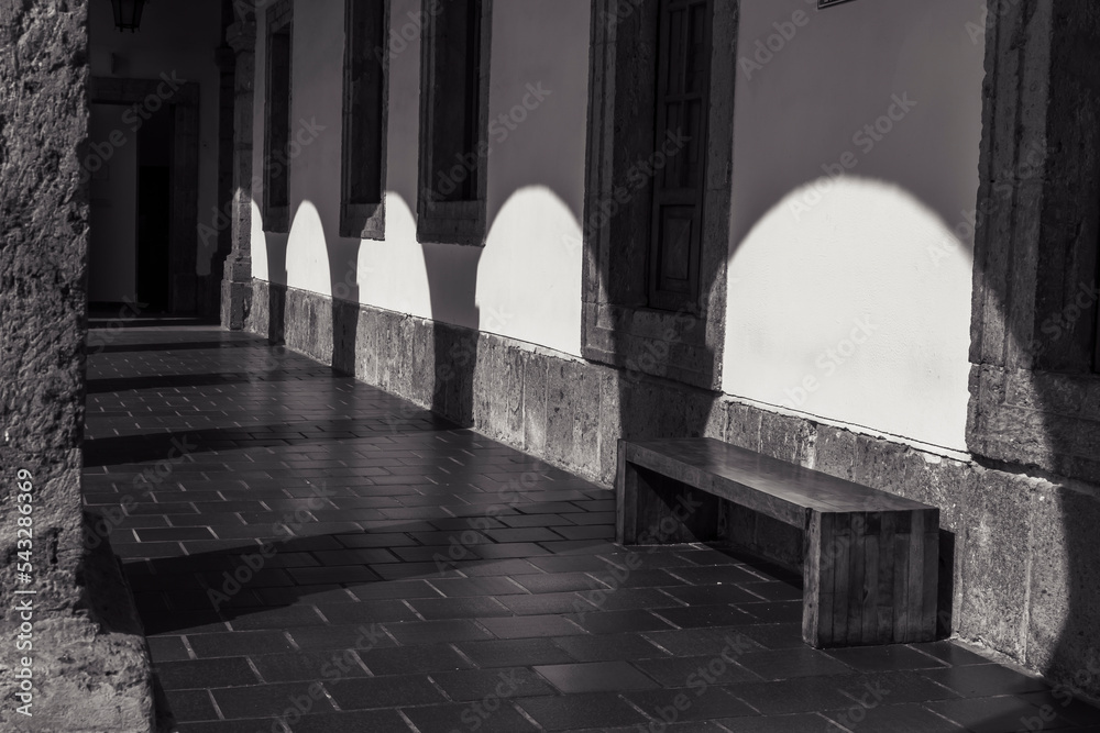 Sunlight passing through some arches and reflecting its shadow on the wall of a corridor.