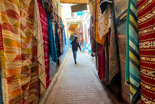 Traditional Moroccan carpets hanging on the street marketplace in the medina of Fez © Mounir