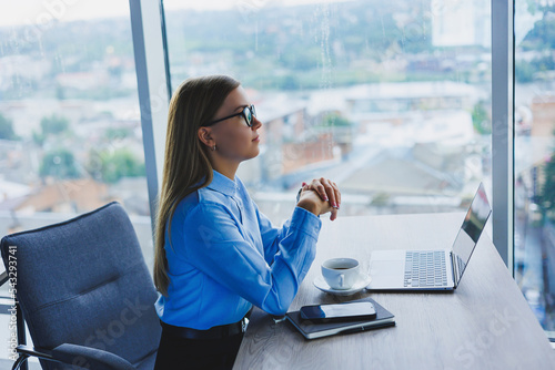 Photos Beautiful business woman in a blue shirt sitting in the office with a laptop and doing business