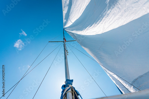 imagen con vista inferior de el mástil de un velero en un día soleado y su vela mayor ondeando por el viento photo