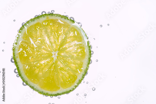 Macro photo of lime slice In water with bubbles isolated on white background. Freshness and healthy lifestyle concept.