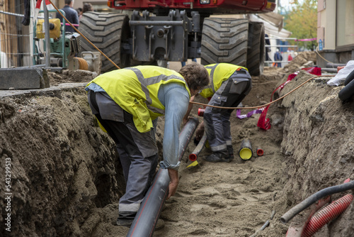 Workers install underground pipes for water, sewerage, electricity and fiber optics for the population of an urban center Fototapet