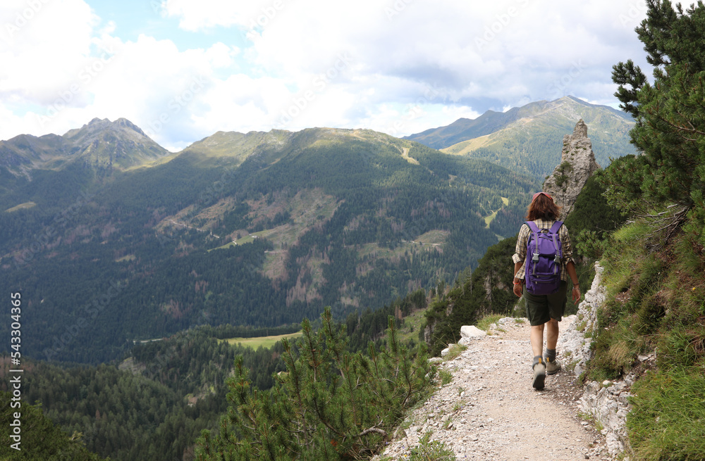Young female hiker walking on the trail in the Italian mountains