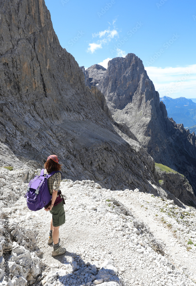 Young female hiker walking on the trail in the Italian mountains
