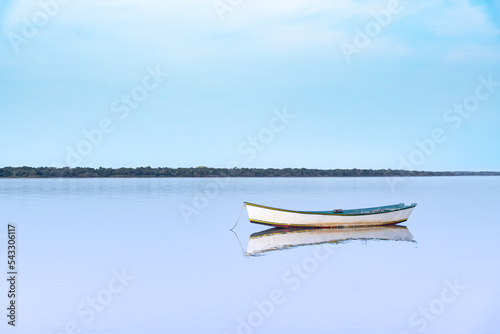 Bote sobre río en calma en tonos celestes