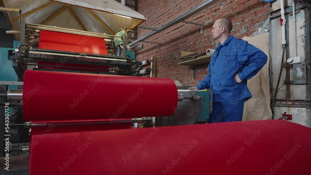 Worker Observes Automated Equipment Processing Fabric At Textile
