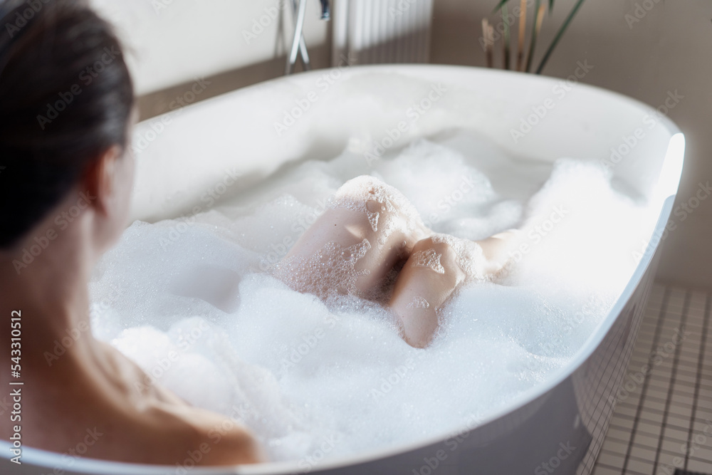 Fototapeta premium Woman taking a bath with hot water and bubbles
