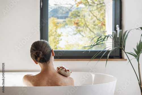 Woman taking hot bath in hotel, looking at window