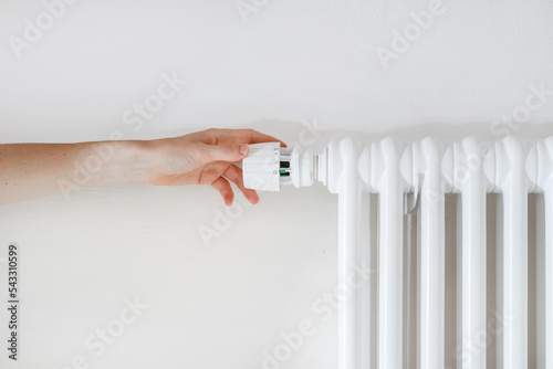 Fotografie Woman hand turning regulator knob on heating radiator in room