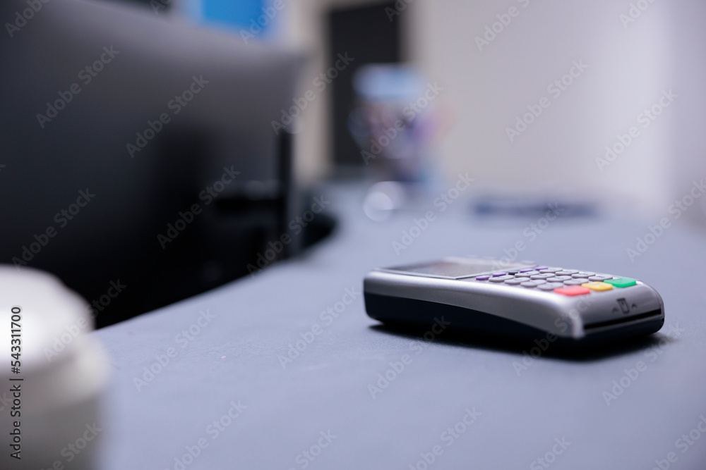 Bank terminal on desk in cashier area of medical institution. Technological gadget to receive payments from patients on counter in medical clinic. Bank card payment collection tool in hospital.