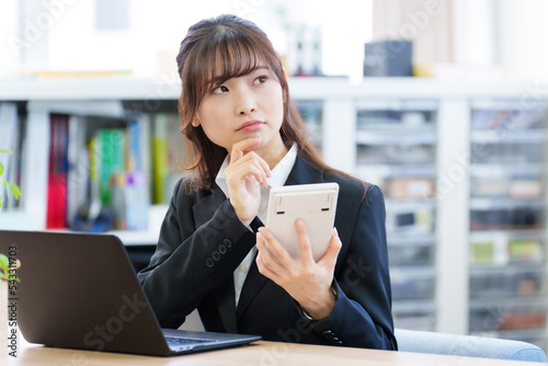 電卓を持って考える女性 photo