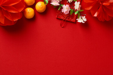Chinese New Year 2023 year of the rabbit. Red packet envelope, flowers, mandarins, festival decorations on red background. Flat lay, top view.