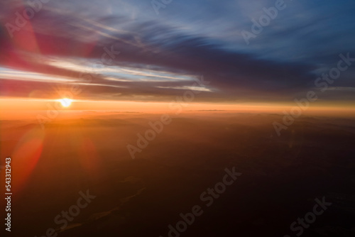 Aerial view of dark mountain hills with bright sunrays of setting sun at sunset. Hazy peaks and misty valleys in evening © bilanol