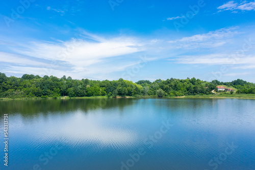 Beautiful landscape with blue water lake and   blurry reflection of meadow and forest surrounding it on the mountain 