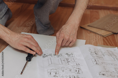 Εκτύπωση καμβά From above of crop man reading paper assembly instruction while assembling furni