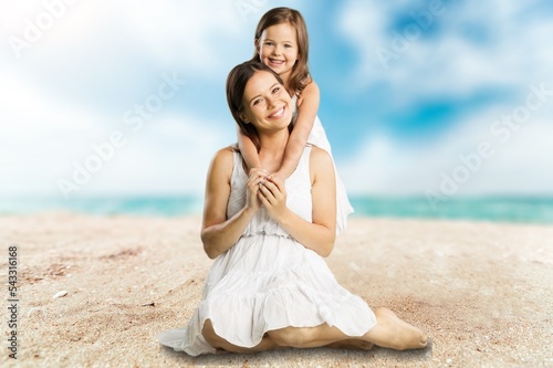 Happy mother and daughter sitting on the beach. © BillionPhotos.com