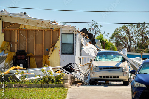 Destroyed by hurricane Ian suburban house and damaged car in Florida mobile home residential area. Consequences of natural disaster