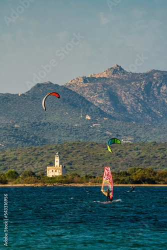 kitesurfing and surfing at the salt pans of Olbia, in the background the Isola Bocca lighthouse, Sardinia