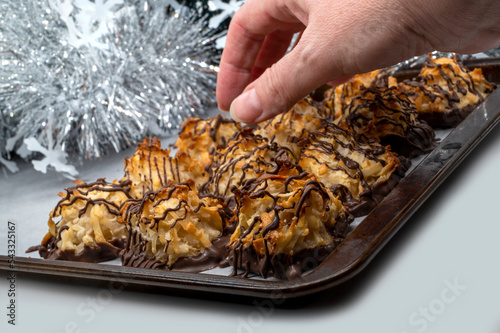 Hand taking cookies. Chocolate drizzled coconut macaroons for Christmas time, selective focus. Homemade cookies with coconut 