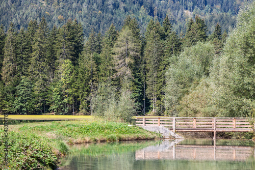 panorama of Plansarsko Jezero lake in Zgornje Jezersko, a typical alpine lake in Slovenia, in the julian alps, with a wooden bridge, in the middle of a fir tree forest, in the Slovenian alps. ... photo