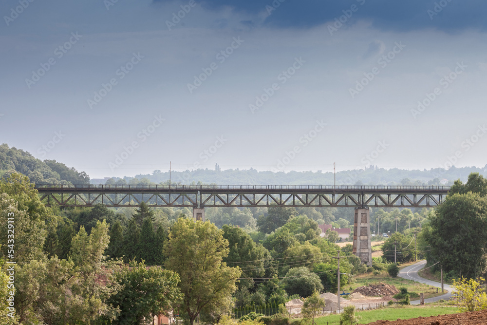 Fototapeta premium Panorama of Serbian nature with an iron steel metal railway bridge of serbian railways crossing a valley with a train infrastucture in summer, in Europe...