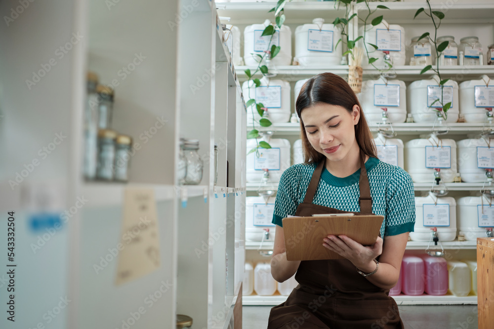 White female shopkeeper checks stock of natural organic products at retail display in refill store, zero-waste and plastic-free grocery shop, eco-friendly, sustainable lifestyles, reusable containers. White female shopkeeper checks stock of natural organic products at retail display in refill store, zero-waste and plastic-free grocery shop, eco-friendly, sustainable lifestyles, reusable containers.
