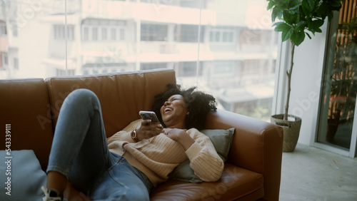 Black woman laughing at a joke on mobile phone