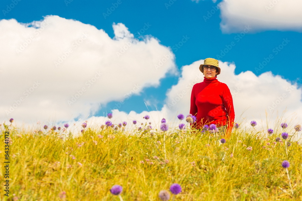 beautiful mature women sits on top of a mountain range and watches into the distance on a summer sunny day beautiful mature women sits on top of a mountain range and watches into the distance on a summer sunny day