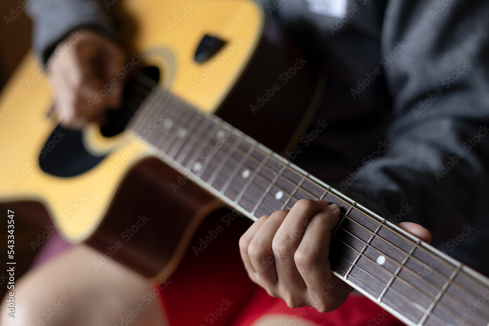 Close Up woman's hands playing acoustic guitar. singer playing guitar on bed, concept of recreation. practise guitar finger style.