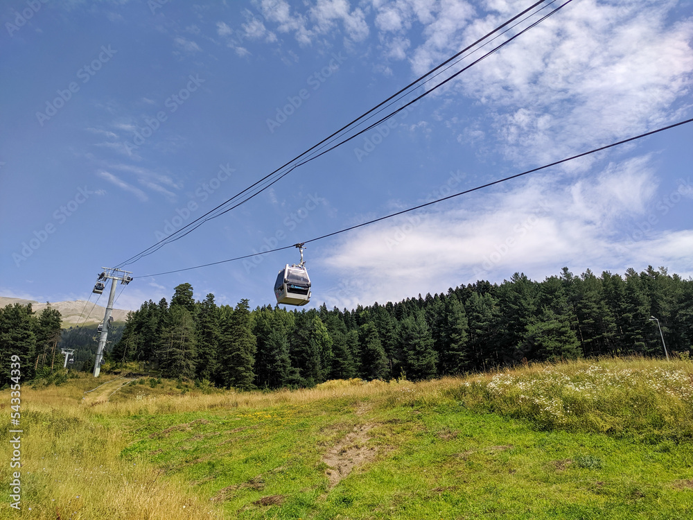 Arkhyz, Karachay-Cherkessia, Russia - August 21, 2022: View of the cable car with cabins in the resort area of Arkhyz against the backdrop of a coniferous forest