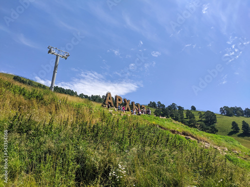 Arkhyz, Karachay-Cherkessia, Russia - August 21, 2022: View of the installation called Arkhyz against the blue sky. People take pictures in the mountains. Translation: Arkhyz